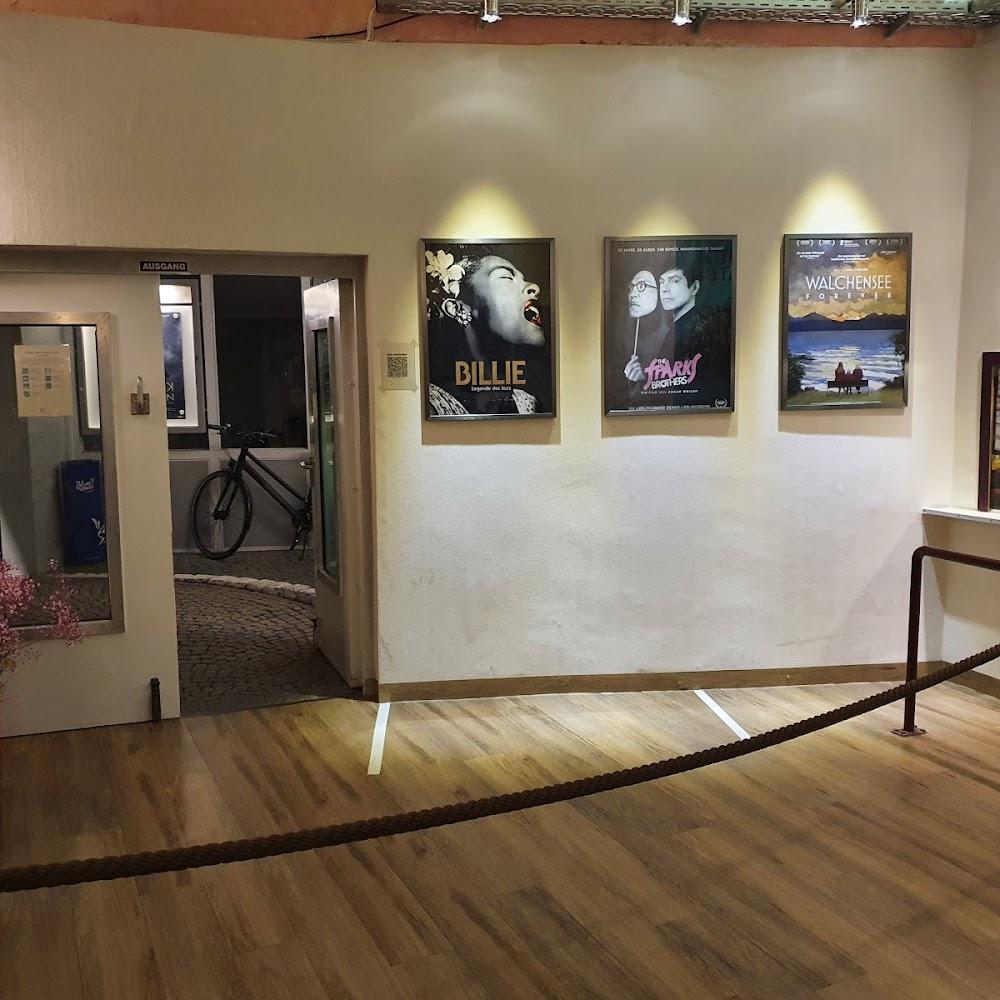 A room with three movie posters and a rope barrier.